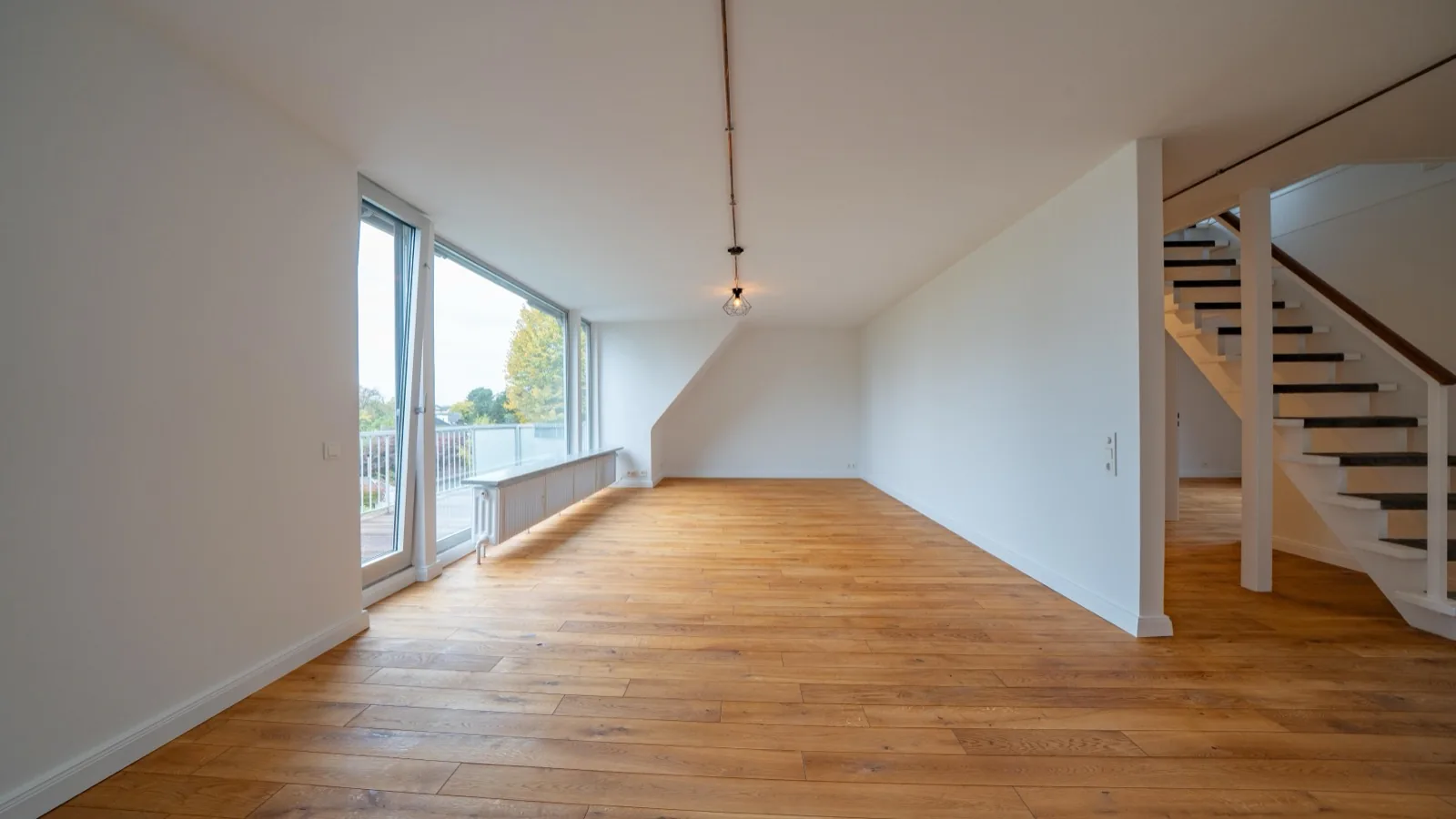 Wohnzimmer nach dem Umbau – heller Raum mit neuem Parkett und Treppenhaus